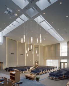 an empty church with blue pews and chandeliers hanging from the ceiling,