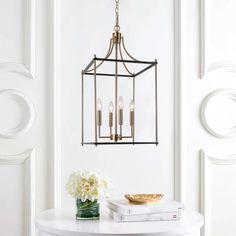 a white table with a vase and some books on it next to a light fixture