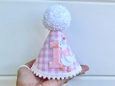 PARTY HAT: $22.95 A party hat made of stiffened felt with light pink gingham fabric, a white party goose beside, trimmed with mini white pom poms on bottom and a white yarn pom pom on the top.  Attached to a 1/8" elastic- to be worn comfortably like a headband.  Size: Small 4"x5.5" 2nd photo is example of how it fits *It's made to order so I'm HAPPY TO CUSTOMIZE TO MATCH YOUR DECOR BEST!! HIGH CHAIR BANNER: $29.95 Three 5"x5.5" scallop shape pink gingham fabric pennants, decorated with white scr Pink Novelty Mini Hat For Birthday, White Hat For First Birthday In Spring, Novelty Pink Mini Hat For Birthday, White Hats For First Birthday In Spring, White Hats For First Birthday And Spring, Pink Gingham Party, Goose First Birthday, Goose Birthday, Hanging Cake