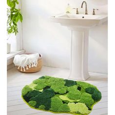 a bathroom with a green rug on the floor next to a white sink and toilet