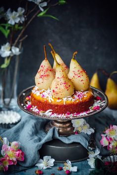 pears on top of a cake with sprinkles and flowers in the background