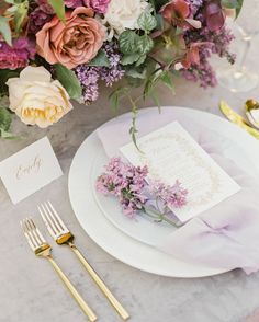 the table is set with purple and white flowers, gold cutlery, and menu cards