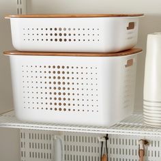 two white storage baskets sitting on top of a shelf