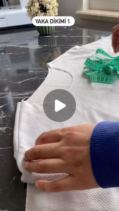 someone is sewing on a piece of cloth with scissors and measuring tape around it, while another person holds their hand over the edge of the fabric