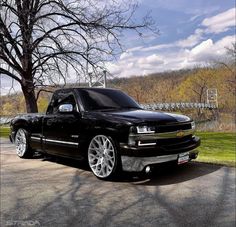 a black truck parked in front of a tree