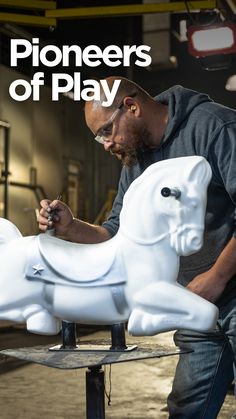 a man is working on a white horse statue with the words pioneers of play in front of him