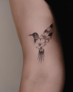 a small bird tattoo on the side of a woman's lower back ribcage