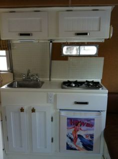 a small kitchen with white cabinets and an oven in it's center island area