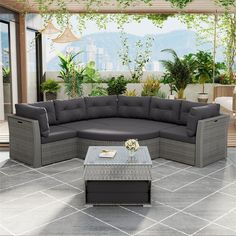 an outdoor living room with grey furniture and plants