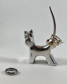 a silver cat figurine next to a wedding ring