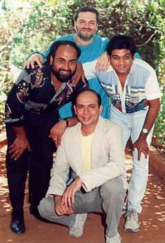 a group of men standing next to each other on a dirt road in front of trees