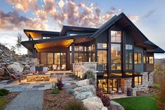 a large house sitting on top of a lush green field next to a hillside covered in rocks