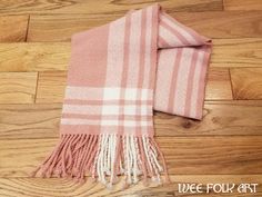 a pink and white plaid scarf laying on top of a wooden floor