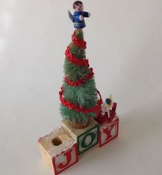 a small christmas tree on top of a toy train with a boy standing on it