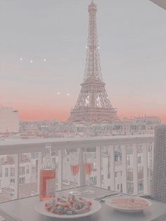 two plates of food on a table in front of the eiffel tower