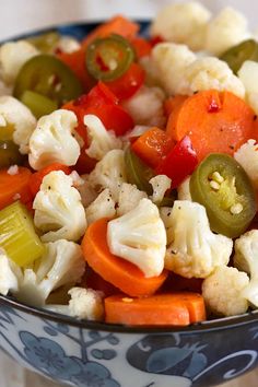 a bowl filled with cauliflower, carrots and jalapeno peppers