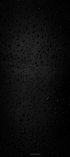 black and white photograph of water droplets on the surface with dark lighting in the background