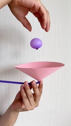 a person is holding a paper boat and an egg in the air with one hand