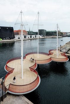 several sail boats floating on top of a body of water next to a pier and buildings