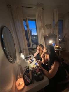 two women sitting at a table in front of a mirror looking at their cell phones