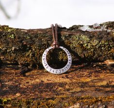 a necklace with the word, trust us on it hanging from a tree branch in front of some moss