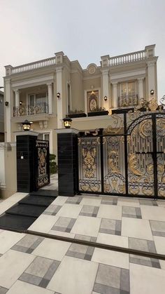 a large white house with black and gold gates