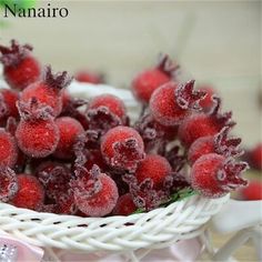 a white basket filled with red berries covered in frosty snow on top of a table