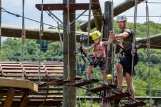 two people on a rope course at the park with safety ropes and climbing equipment around them