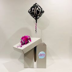 a black and white balloon is in the shape of a table with a pink flower on it