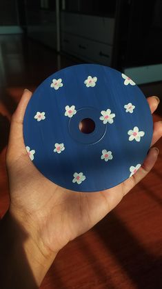 a hand holding a blue object with white flowers on it