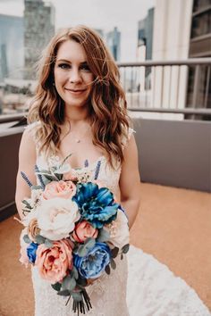 a woman holding a bouquet of flowers on top of a roof in front of the city