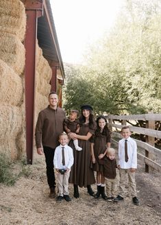 a family poses for a photo in front of a barn with hay bales behind them