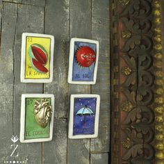 four tiles with different designs on them sitting on a wooden table next to a wall