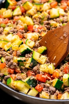 a skillet filled with meat and veggies on top of a wooden spoon