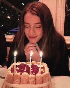 a woman sitting in front of a cake with candles