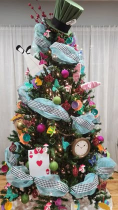 a small christmas tree decorated with blue and green ribbons, hats, and other decorations