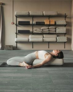 a woman is doing yoga on the floor in front of shelves with folded towels and linens