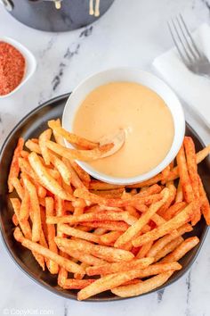 french fries on a plate with dipping sauce in the bowl next to it and other ingredients