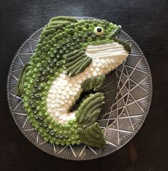 a cake made to look like a fish on top of a metal plate with white and green icing