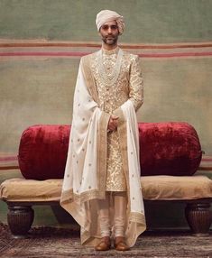 a man in a turban standing next to a couch