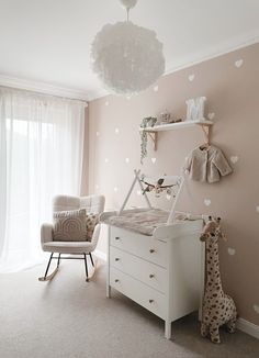 a baby's room with pink walls and white furniture