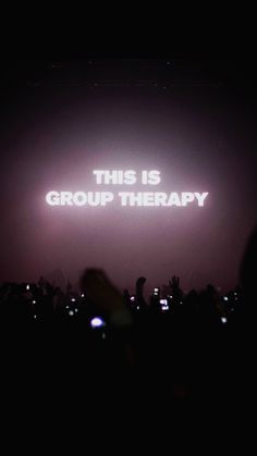 the words'this is group therapy'are projected in front of a crowd at a concert