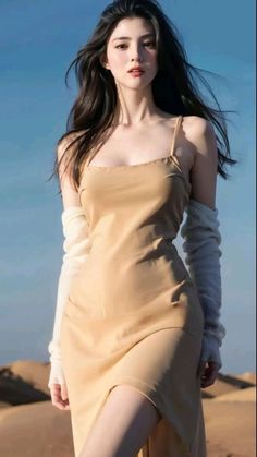 a woman with long hair wearing a tan dress and heels standing in the sand dunes