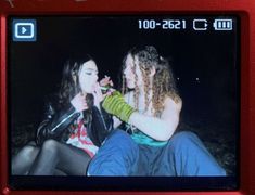 two young women sitting next to each other in front of a red camera with the screen showing