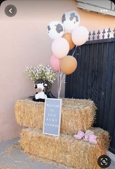 a hay bale with balloons and baby's breath sign on it in front of a gate