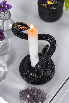 a white candle sitting on top of a table next to some rocks and flowers in vases