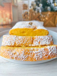 two pieces of bread on a plate with powdered sugar and christmas tree in the background