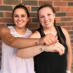 two girls with tattoos on their arms posing for the camera, one is holding the arm of another girl