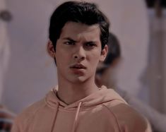 a young man in a pink hoodie looking at the camera