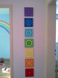 four colorful paintings are hanging on the wall in front of a child's room